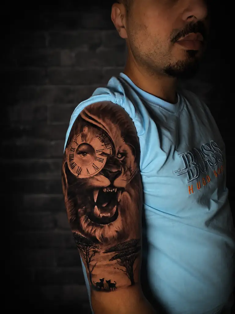 Realism lion and clock tattoo on the upper arm.