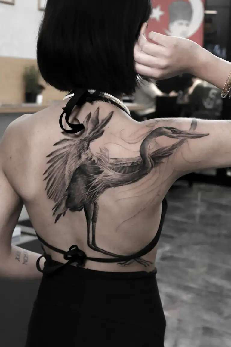 Black and grey illustrative realism large-scale bird backpiece tattoo.